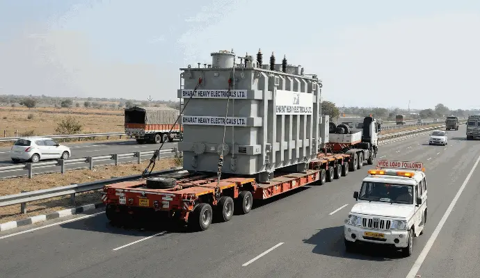Over-dimensional cargo (ODC) transport of heavy machinery on low-bed trailer."